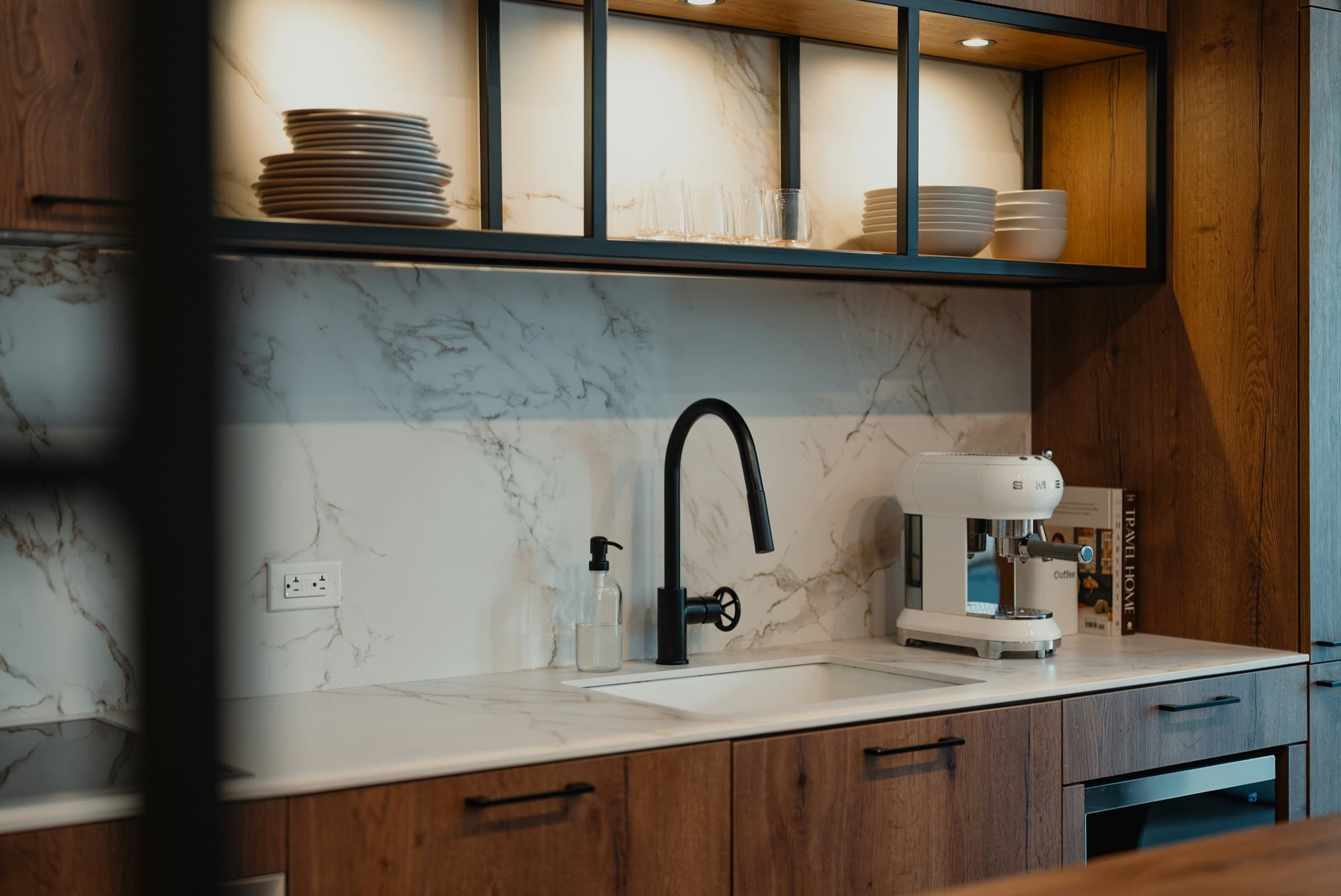 Premium kitchen sink with black faucet, marble backsplash and warm cabinetry