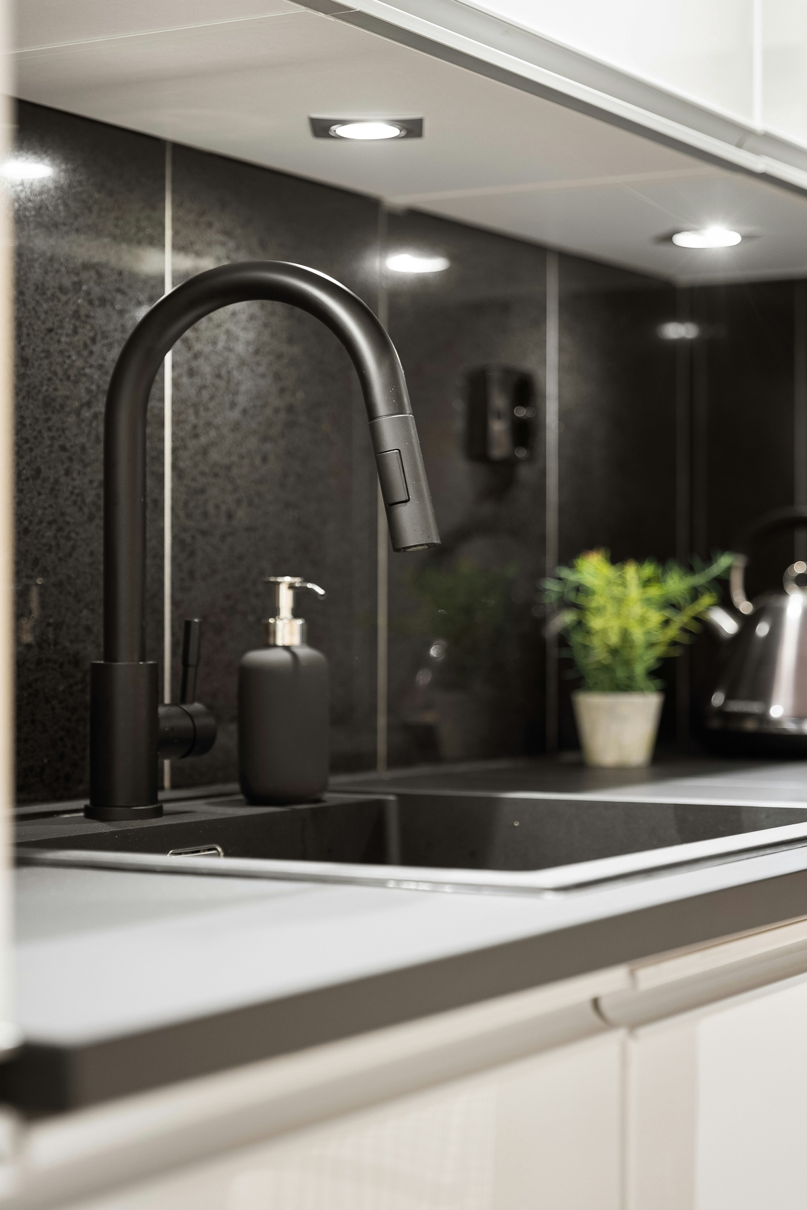 Matte black kitchen faucet with dark backsplash and counter styling