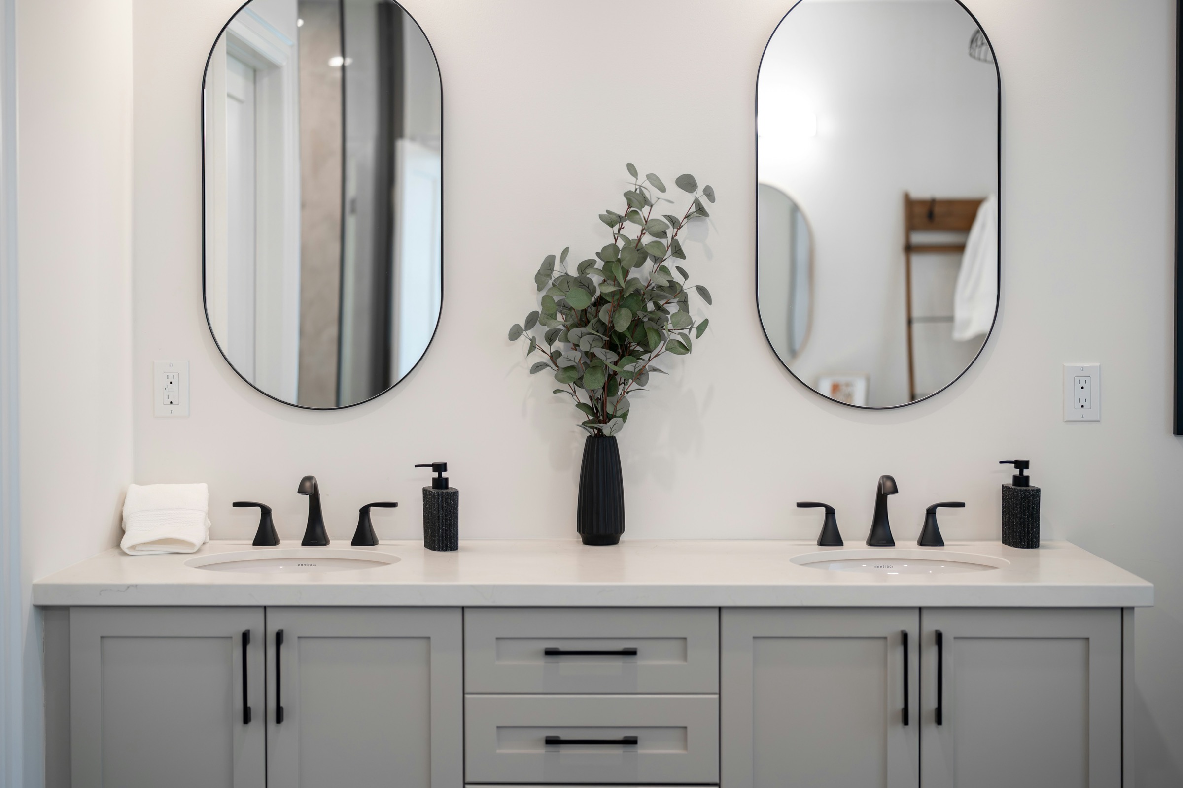 Double vanity with oval mirrors and matte black fittings